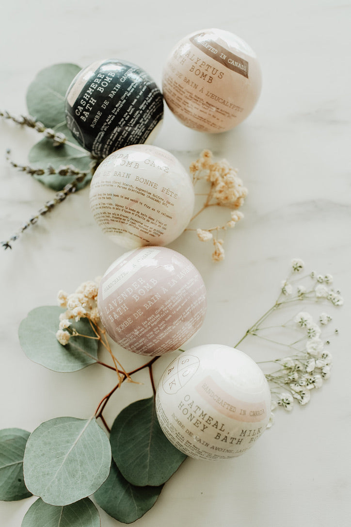 Bath bombs with text labels on a light surface with greenery
