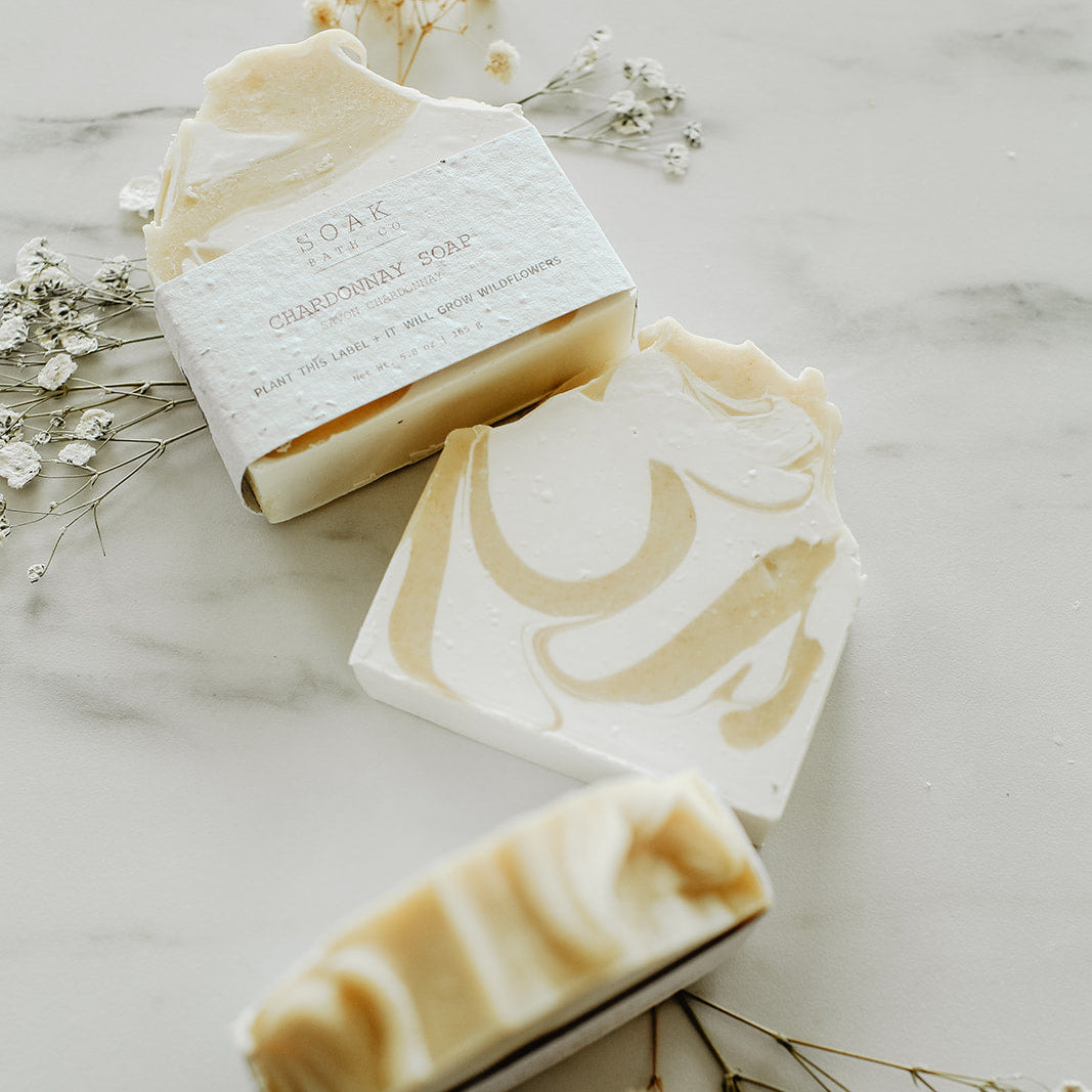 Three bars of soap with decorative designs on a marble surface with small flowers.