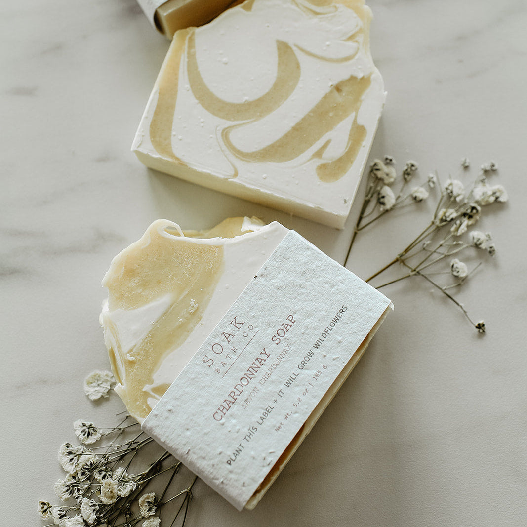 Three bars of soap with decorative designs on a marble surface with small white flowers.