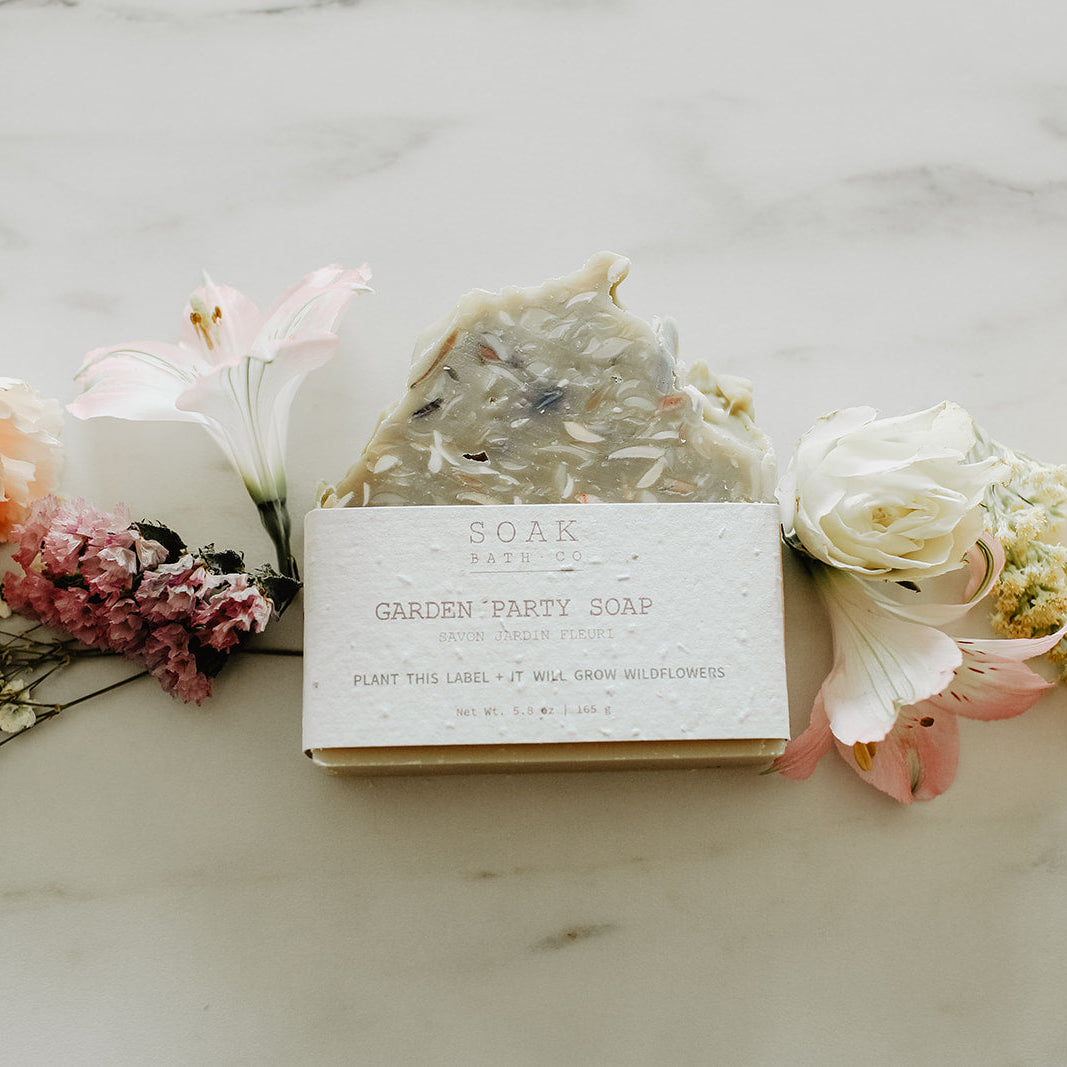Bar of soap with a label surrounded by flowers on a marble surface
