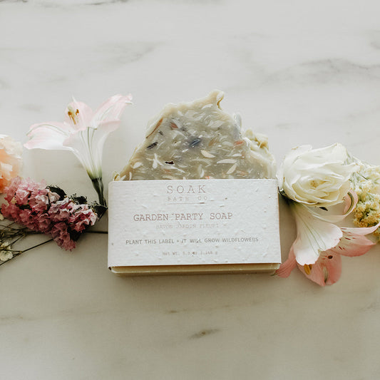 Bar of soap with a label surrounded by flowers on a marble surface