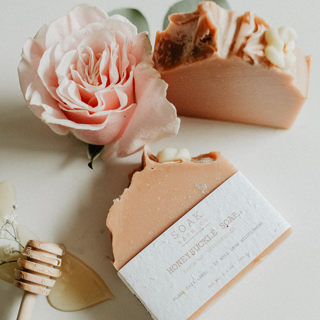 Two bars of soap with a pink rose on a light surface
