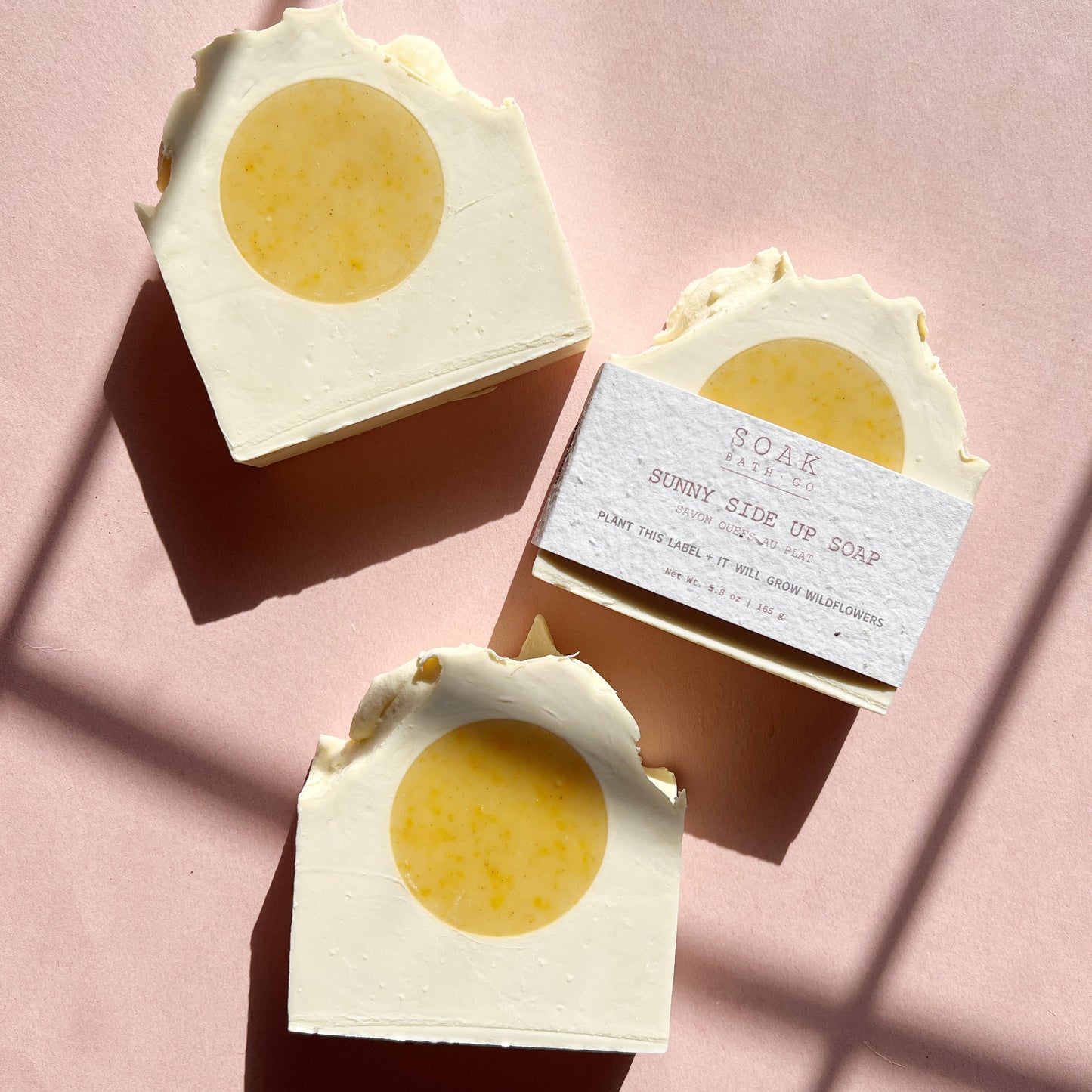 Three soap bars with a circular yellow center on a pink background