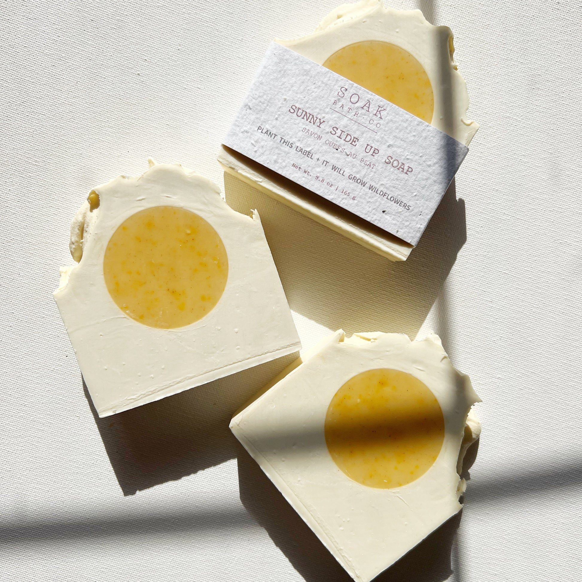 Three bars of soap with a yellow center on a light gray background