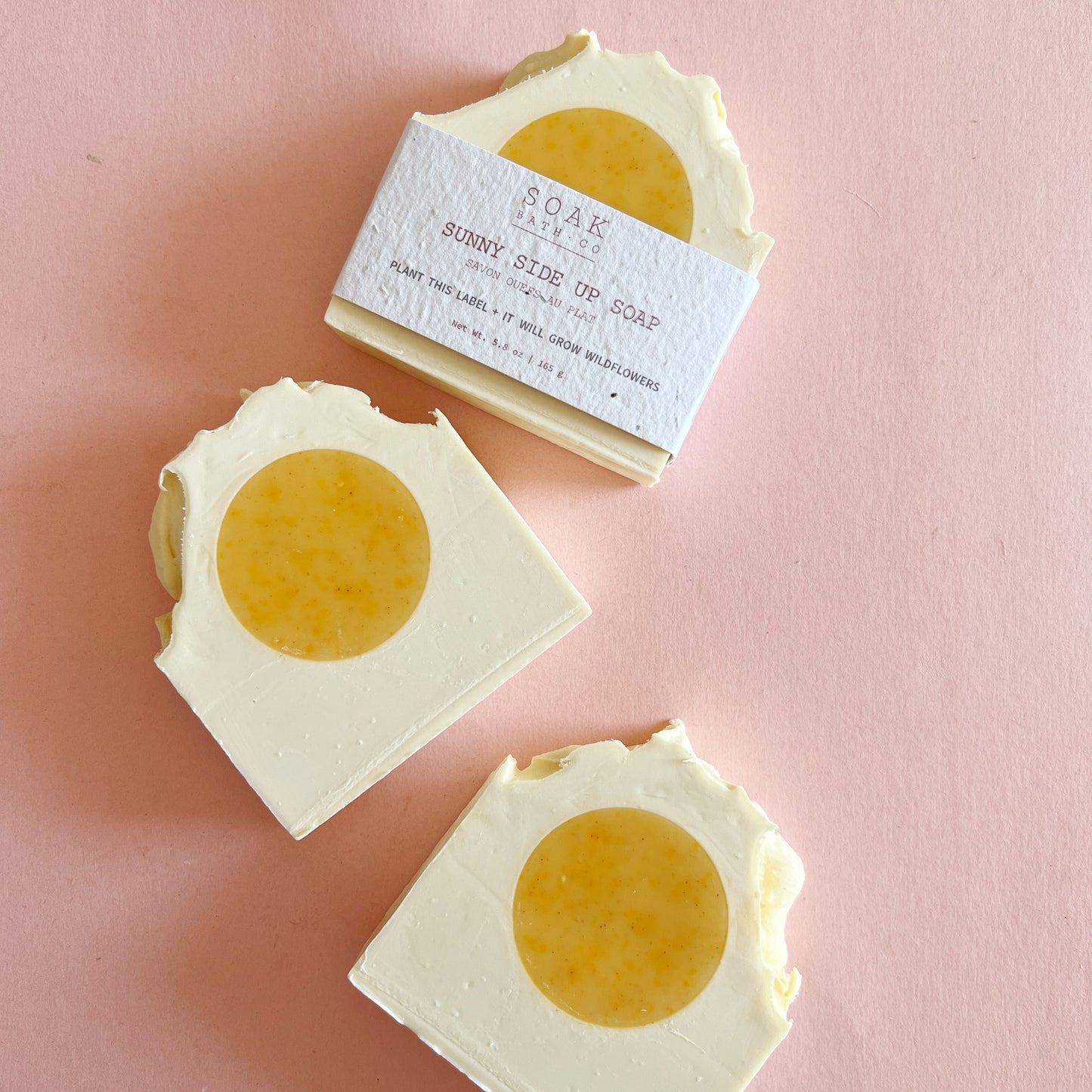 Three bars of soap with a yellow center on a pink background
