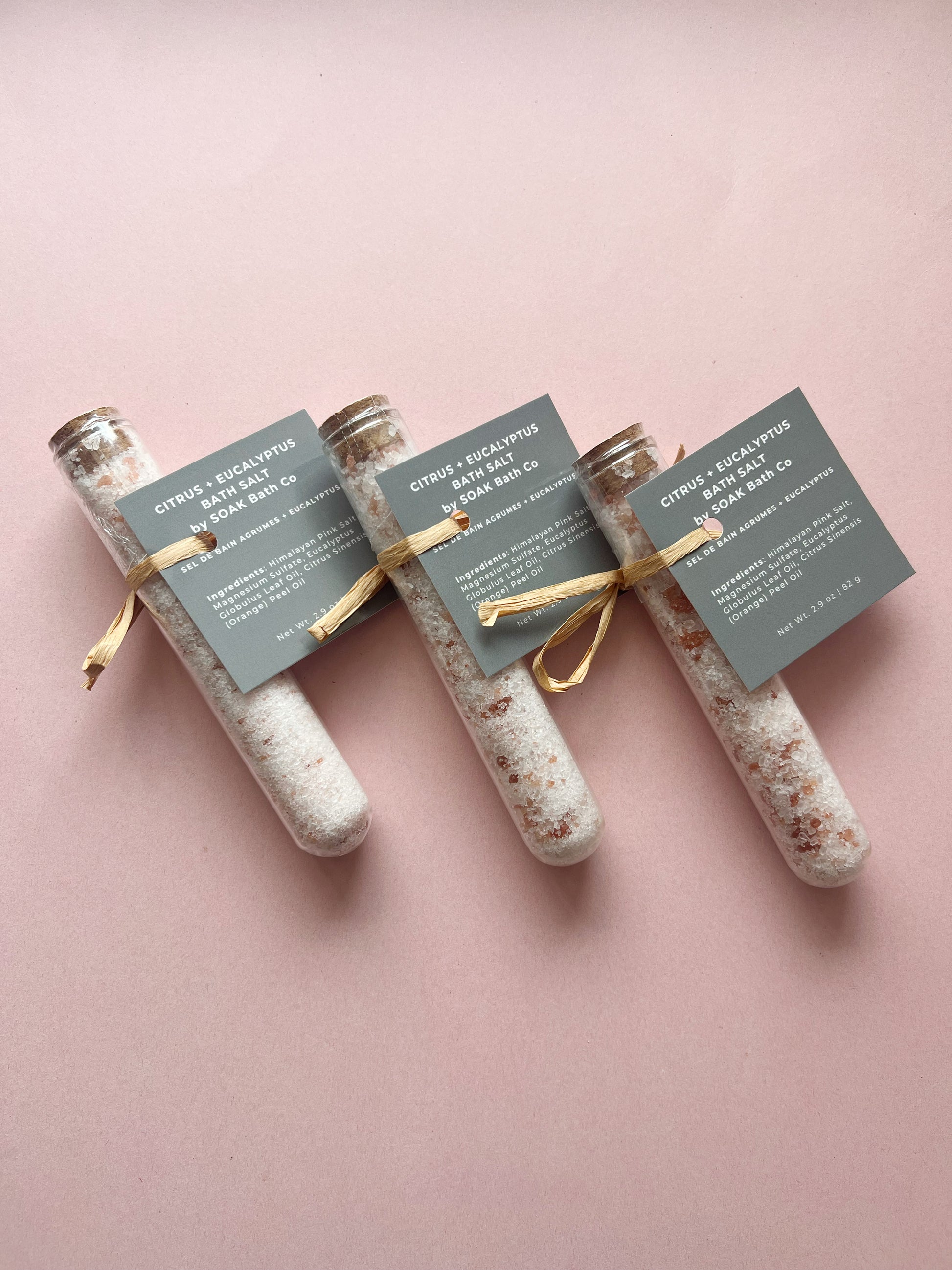 Three test tube-shaped containers with decorative labels on a pink background