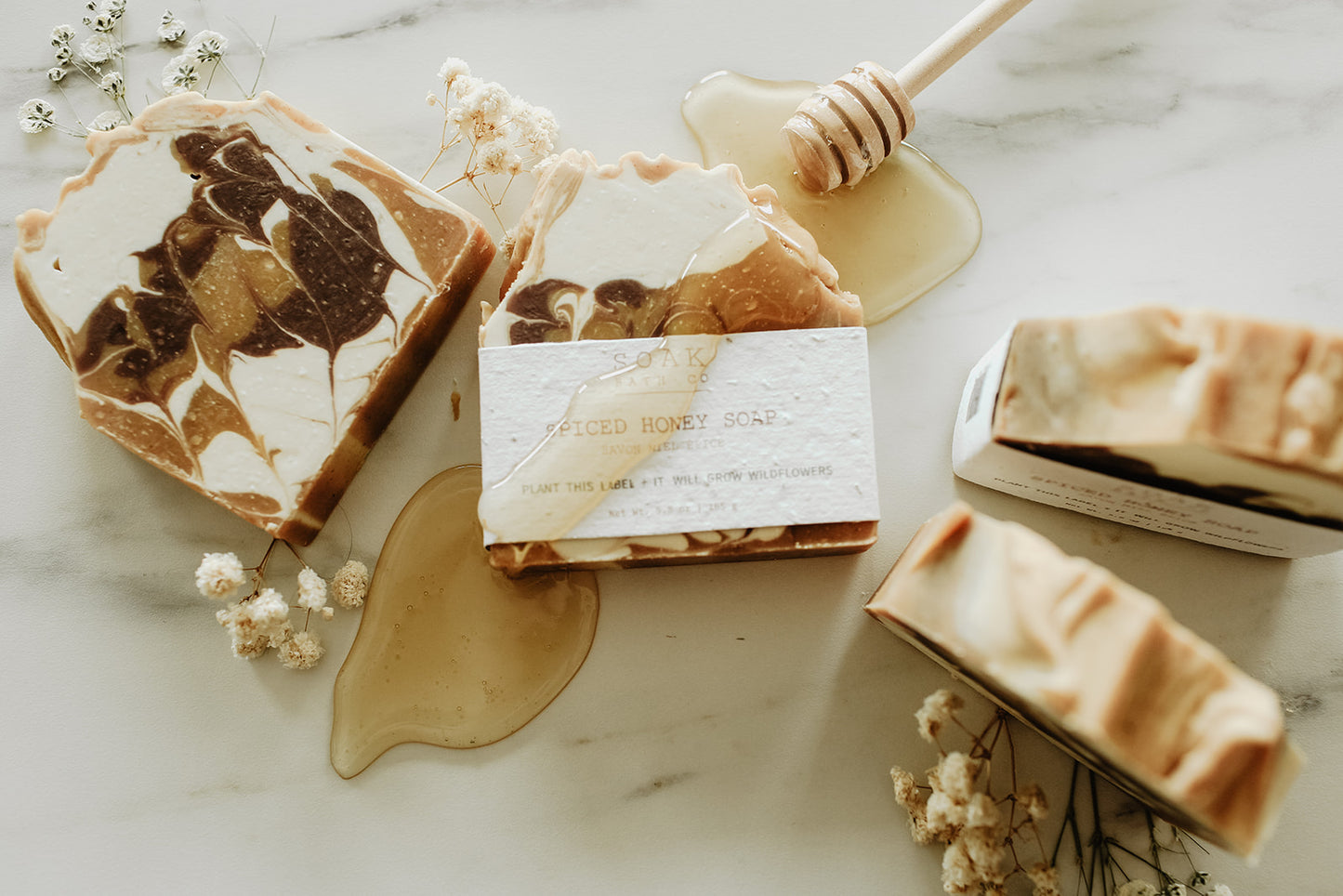 Marble-patterned soap bars with honeycomb and flowers on a marble surface