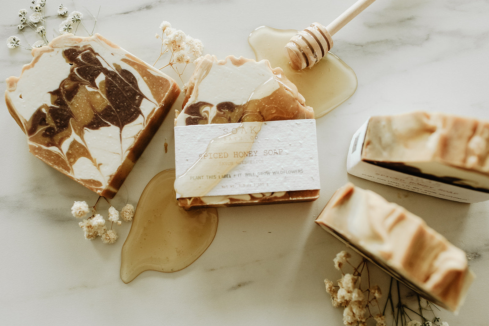 Marble-patterned soap bars with honeycomb and flowers on a marble surface