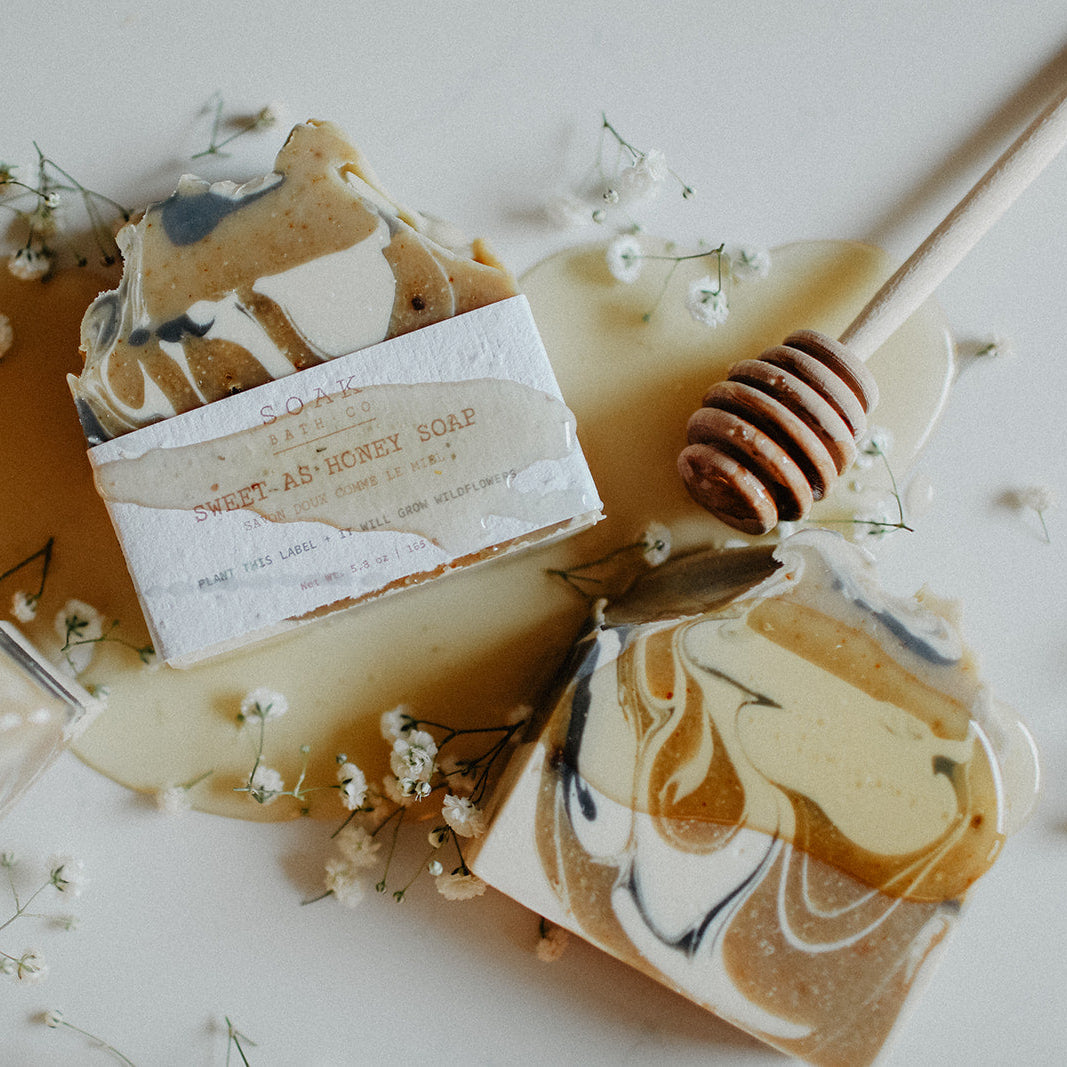 Marbled soap bars with a honey dipper and flowers on a white background