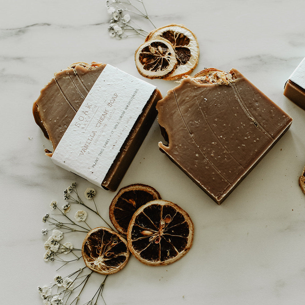 Chocolate bars with white labels on a marble surface with dried oranges and flowers.