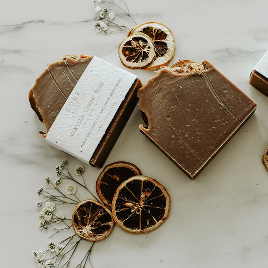Chocolate bars with white labels on a marble surface with dried oranges and flowers.